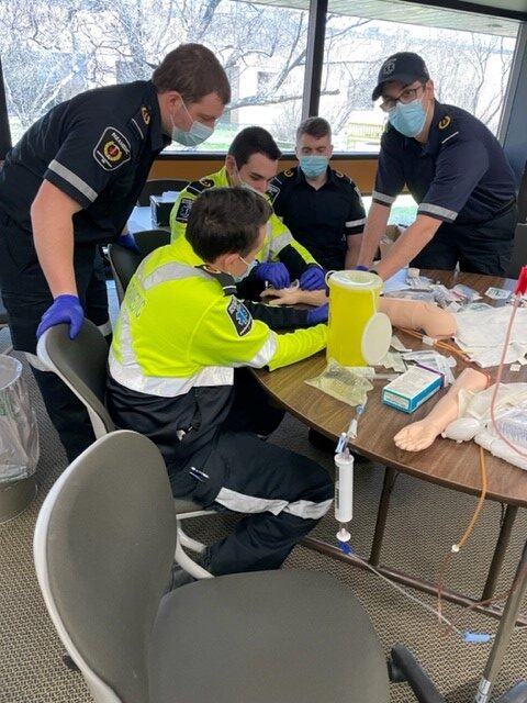 new paramedics gather around a table to become IV certified.
