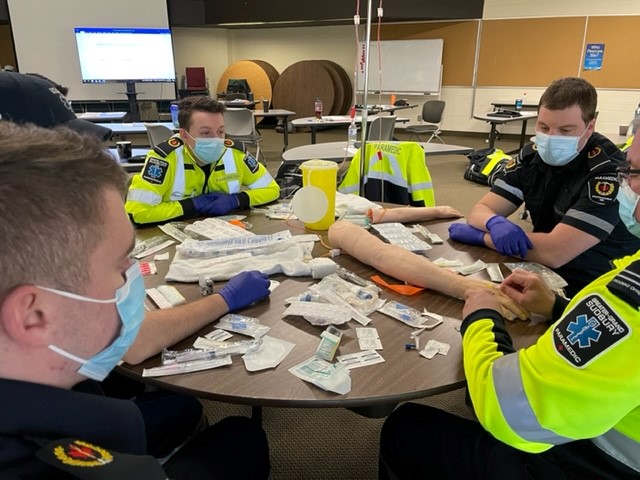 paramedics sitting at a round table training for IV certification